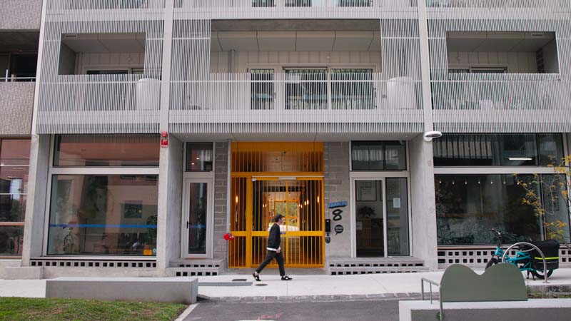 man walking in front of apartment buildings