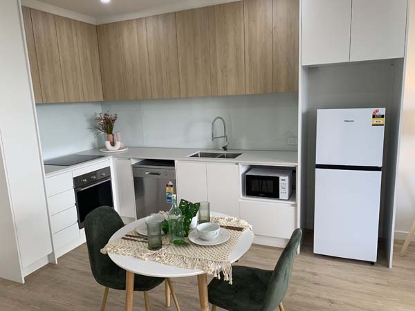 kitchen setting with table fridge sink and cupboards