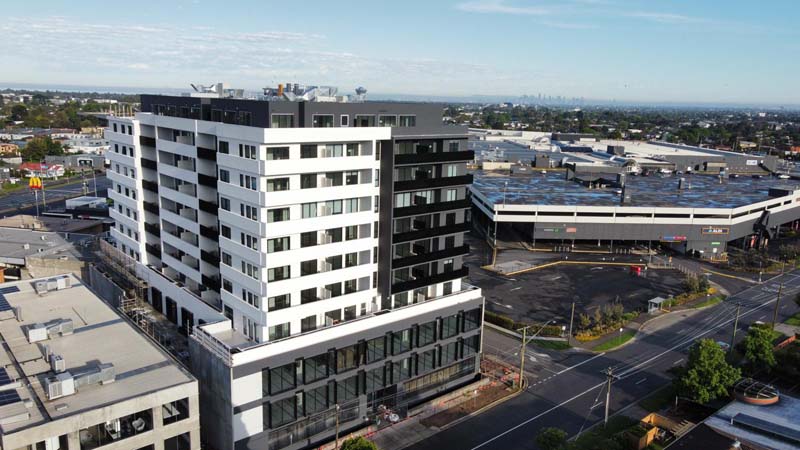 Wide shot of a black and white apartment building and the street in front