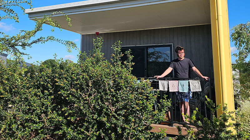 Image of young man standing at his balcony and enjoying nature outdoor