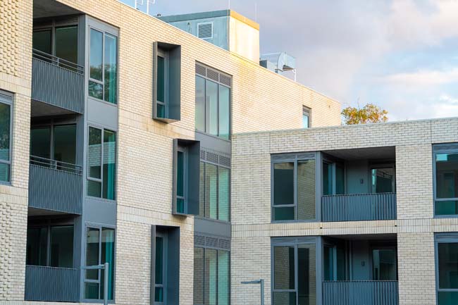 Image of apartments with white bricks having big windows and balcony