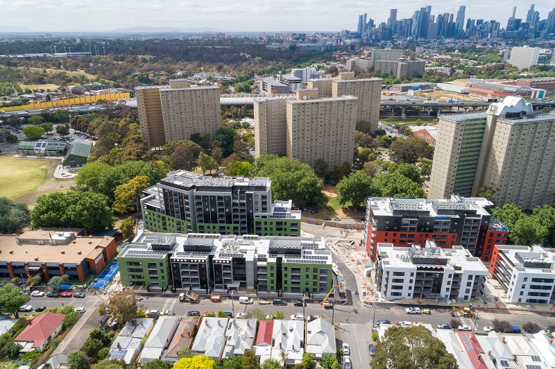 Drone image of high rise redevelopment tower surrounded with green trees, oval and local community