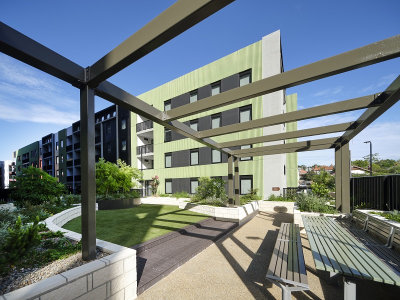 Image of outdoor space with bench and table for family and friends to sit or party as well as greenery around