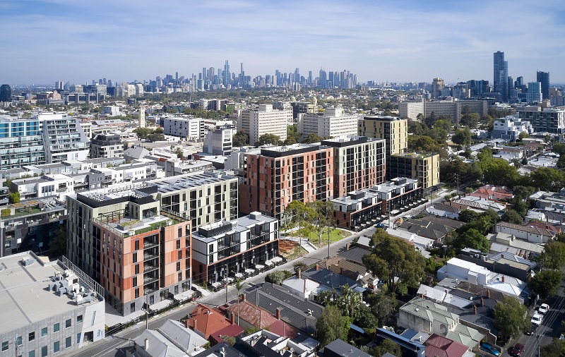 Drone image of the Bangs Street housing development surrounded with green trees, oval and local community