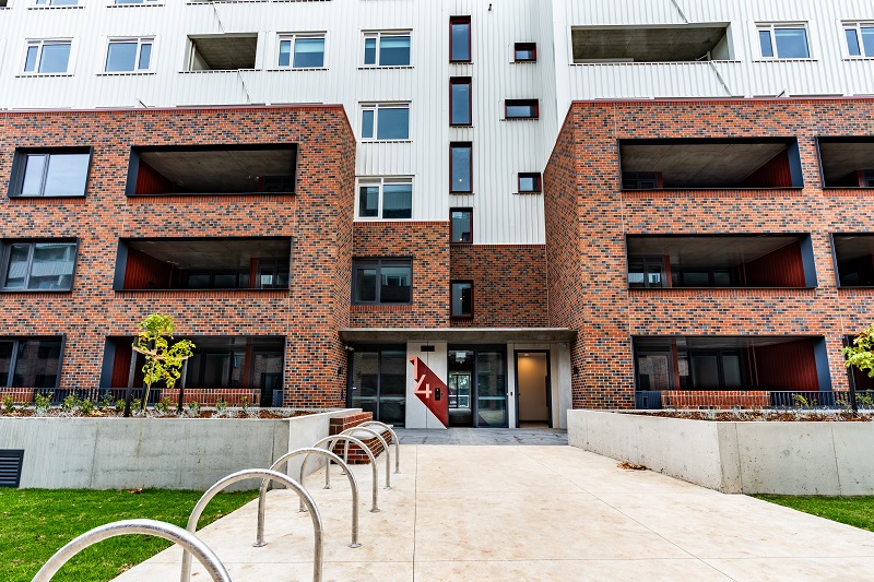 Close-up Image of Social housing building located along Kitchner Street, Brunswick  West.having red bricks and bi windows surrounded with greenery.