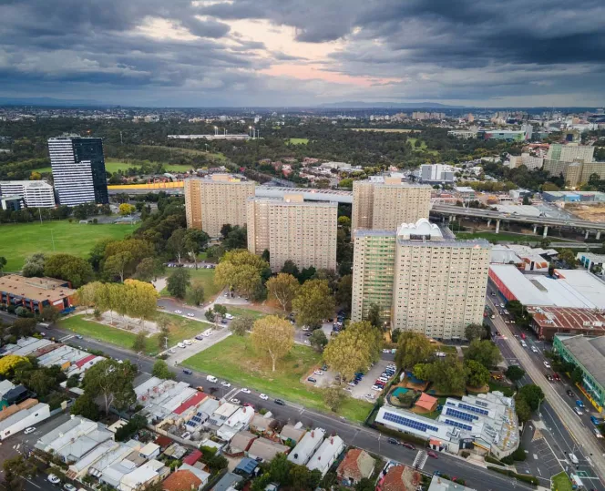 Drone image of high rise redevelopment tower surrounded with green trees, oval and local community