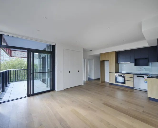 Open-plan living with kitchen along the wall and a door to the balcony