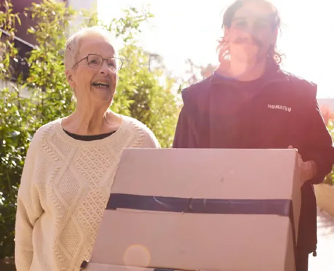 2 people smiling while moving boxes