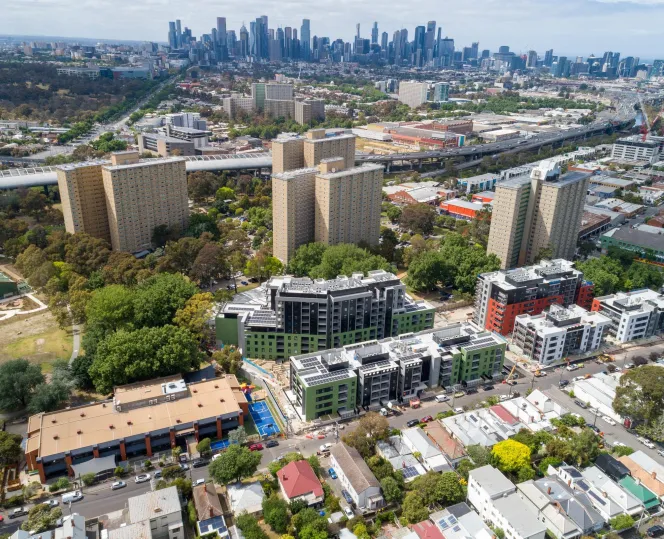 Aerial image of 4 apartment towers with buildings around them, the city skyline can be seen in the background