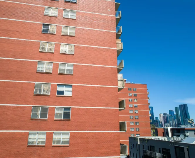 Apartment block made of red bricks with a similar one in the background and the city skyline