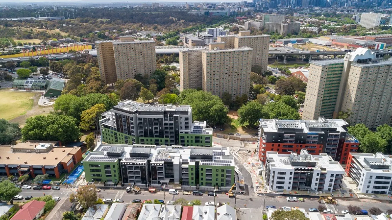 Drone image of high rise redevelopment tower surrounded with green trees, oval and local community